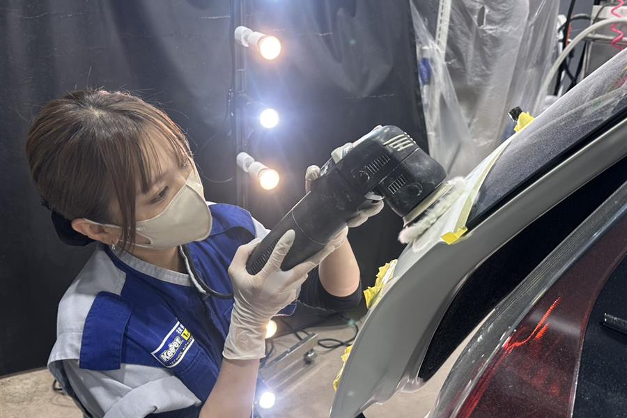 専用ライトの下でポリッシャーを使い塗装を研磨するスタッフ